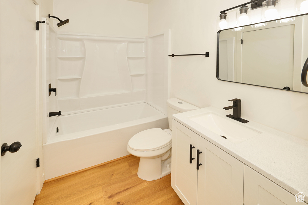 Full bathroom featuring wood finished floors, toilet, shower / washtub combination, and vanity