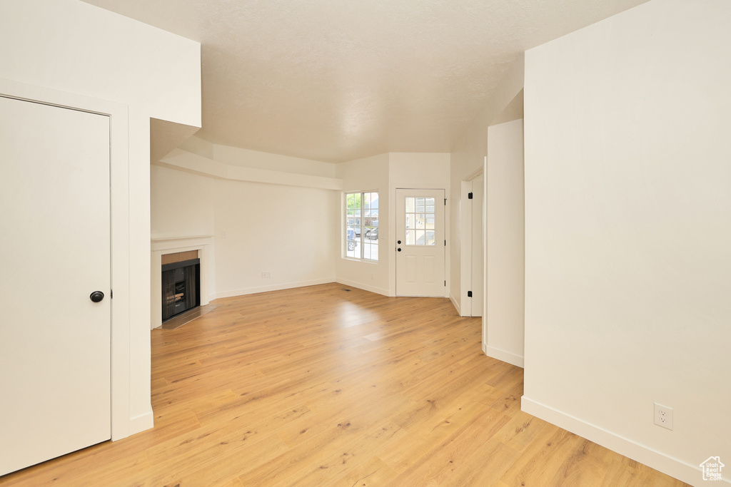 Unfurnished living room with a fireplace, baseboards, and light wood finished floors