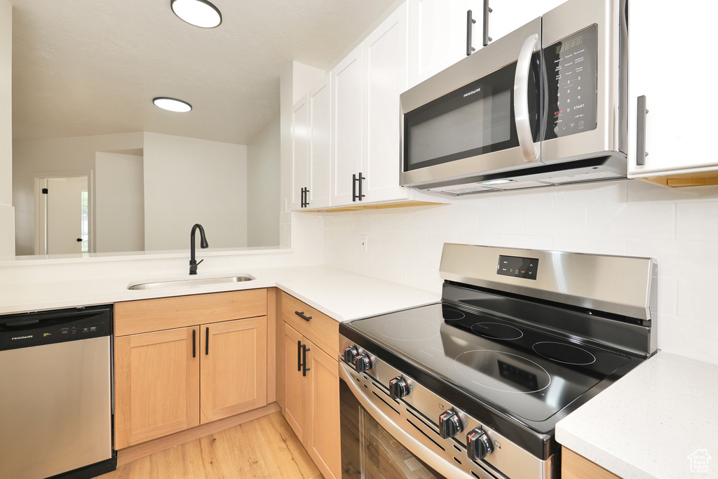 Kitchen featuring appliances with stainless steel finishes, a sink, light countertops, light wood finished floors, and recessed lighting