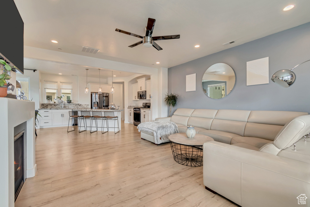 Living room featuring light wood-style flooring, a ceiling fan, and recessed lighting