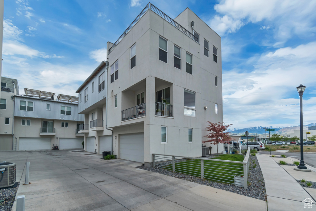 View of property featuring an attached garage, central AC, driveway, and a mountain view