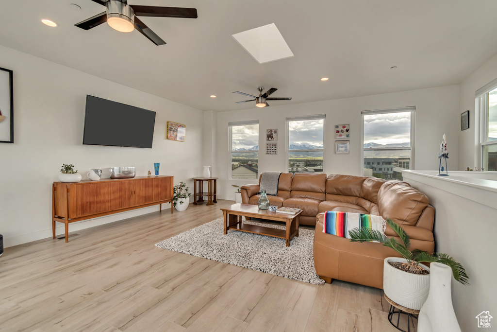 Living room featuring ceiling fan, wood finished floors, a skylight, and recessed lighting