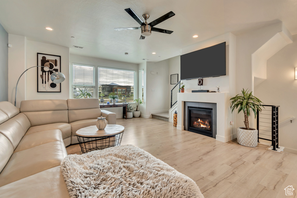 Living area with ceiling fan, wood finished floors, baseboards, recessed lighting, and a glass covered fireplace