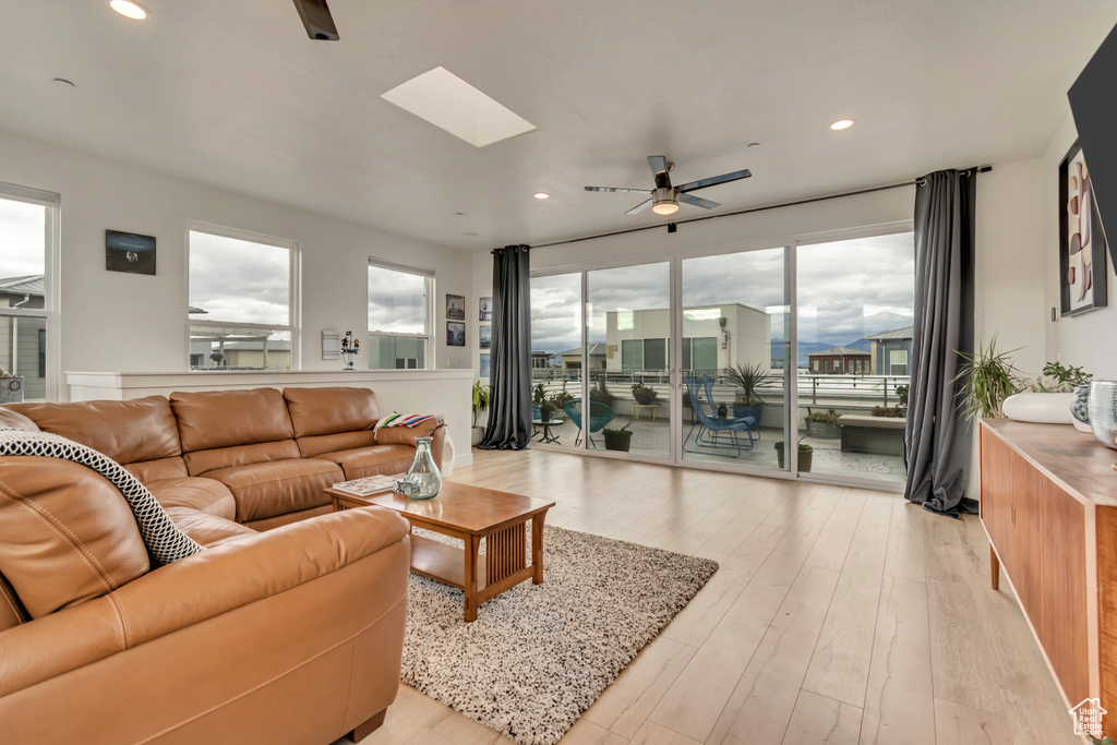 Living area featuring ceiling fan, a skylight, light wood finished floors, and recessed lighting