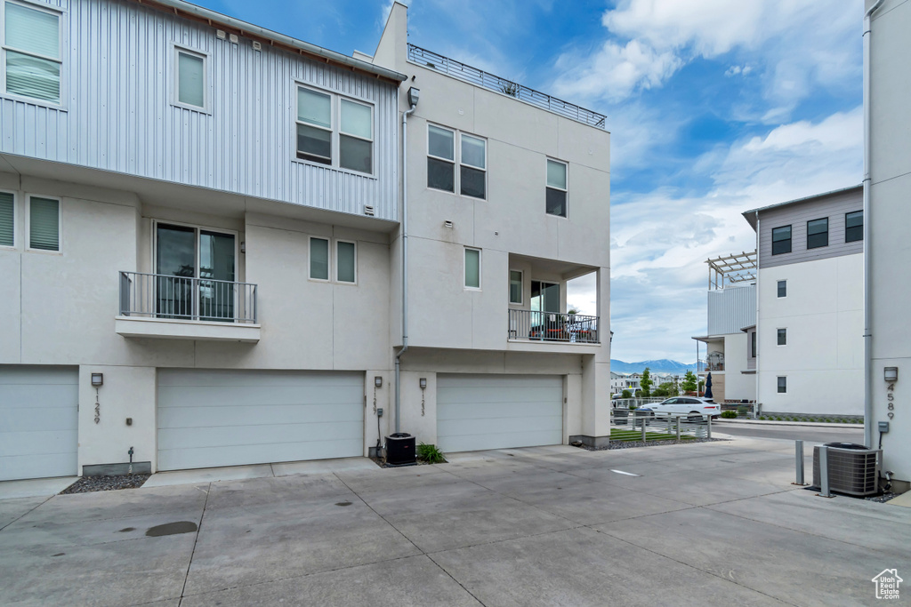 Rear view of house with cooling unit, a garage, driveway, stucco siding, and a mountain view