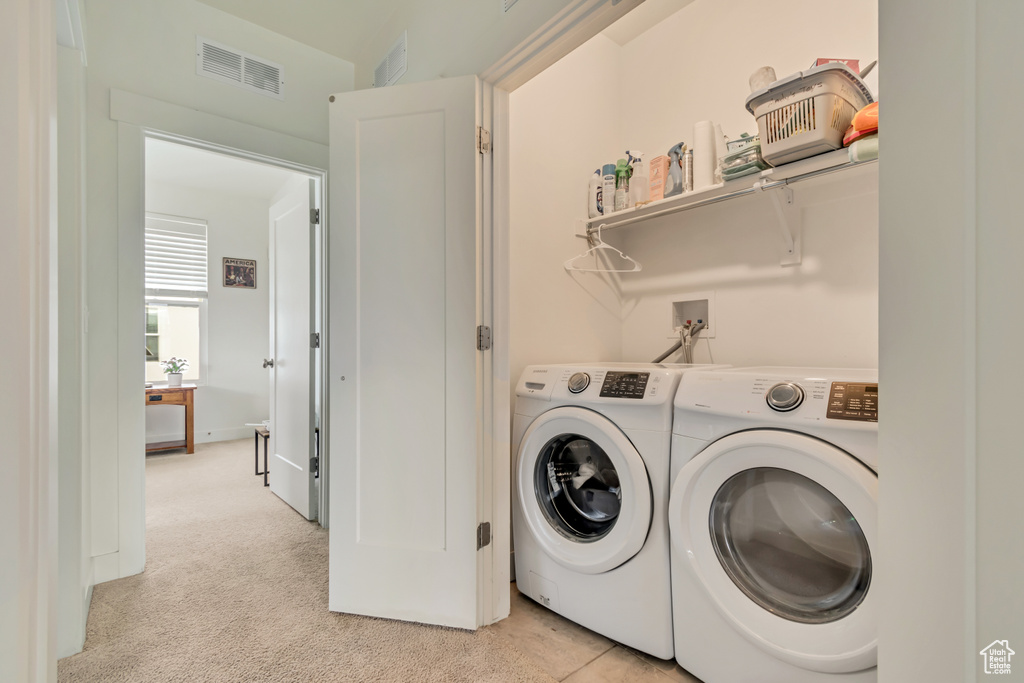 Clothes washing area featuring separate washer and dryer and light colored carpet