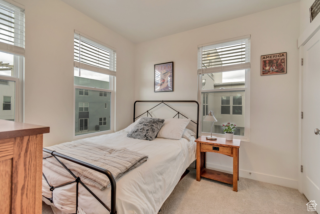 Bedroom featuring multiple windows, light colored carpet, and baseboards