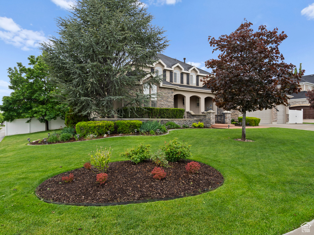 View of front of house featuring stone siding, driveway, stucco siding, and a garage