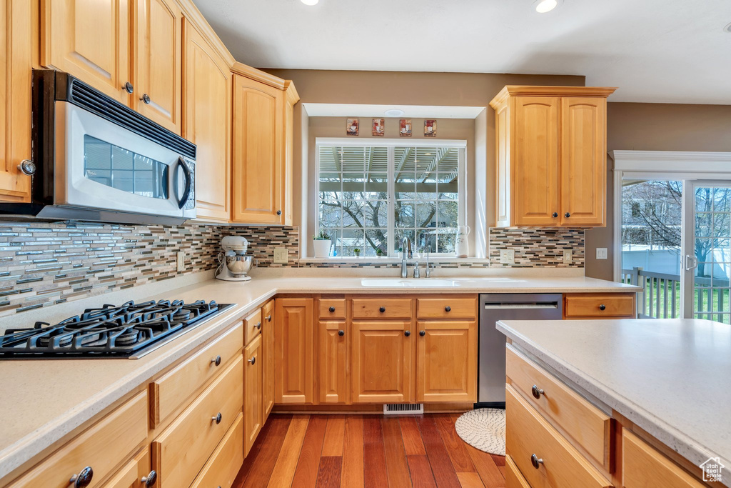 Kitchen featuring appliances with stainless steel finishes, a sink, light brown cabinetry, recessed lighting, and light countertops