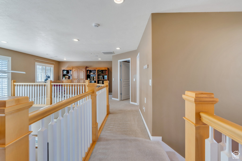 Hallway with an upstairs landing, light carpet, baseboards, and recessed lighting