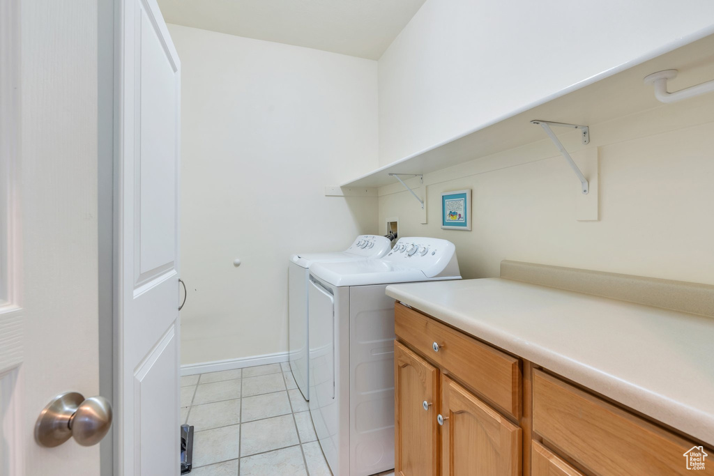 Laundry area featuring separate washer and dryer, light tile patterned floors, baseboards, and cabinet space
