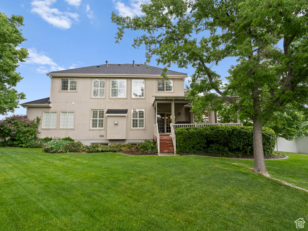 Rear view of house featuring stucco siding and a yard