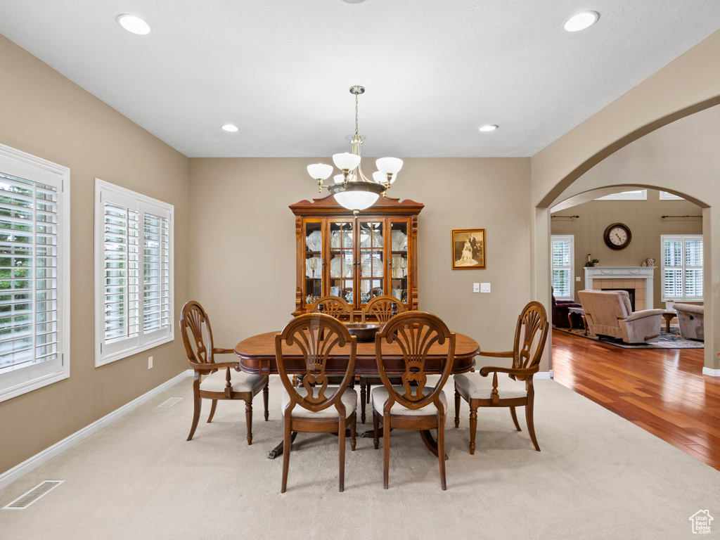 Dining room featuring a chandelier, arched walkways, light carpet, recessed lighting, and a fireplace