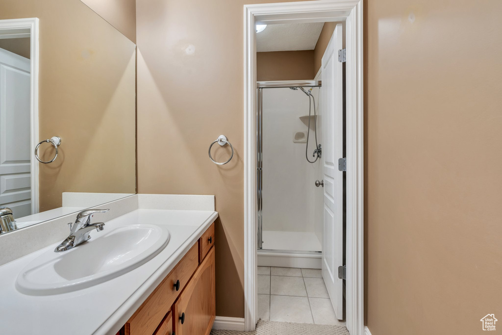 Full bath featuring a shower stall, tile patterned flooring, vanity, and baseboards