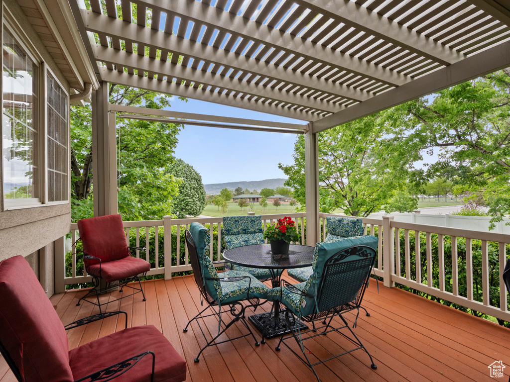 Wooden terrace featuring outdoor dining space, a pergola, and a mountain view