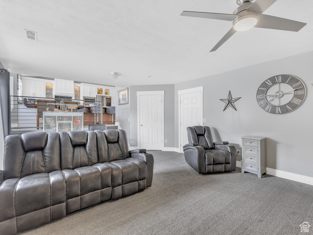 Living area featuring baseboards, ceiling fan, and carpet flooring
