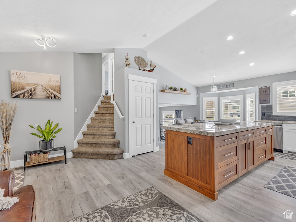 Kitchen with open shelves, light wood finished floors, lofted ceiling, recessed lighting, and a kitchen island
