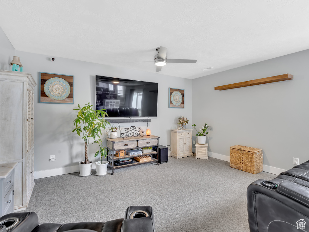 Carpeted living room with ceiling fan and baseboards
