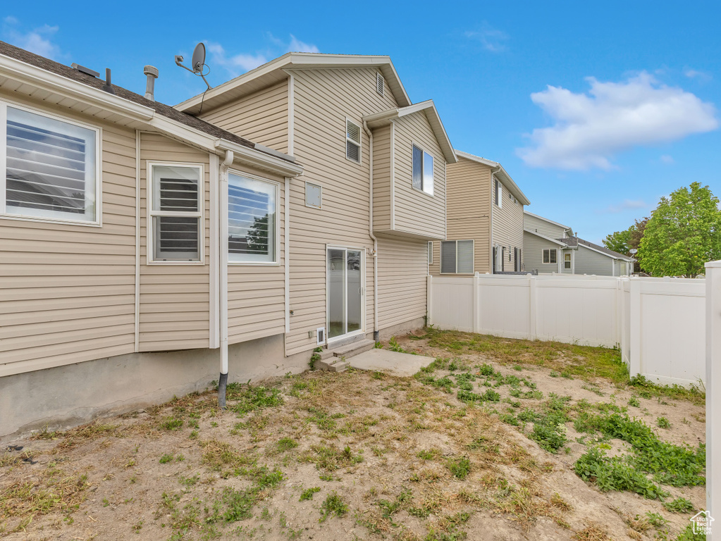 Rear view of house with entry steps and fence