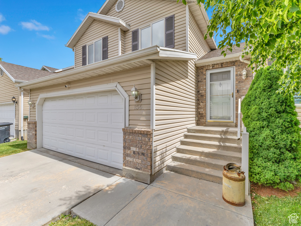 View of front of home with an attached garage, driveway, roof with shingles, and entry steps