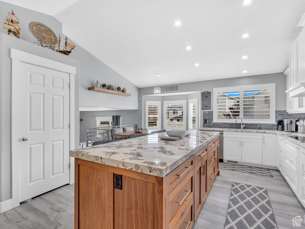 Kitchen with a kitchen island, light wood-style flooring, recessed lighting, backsplash, and light stone counters