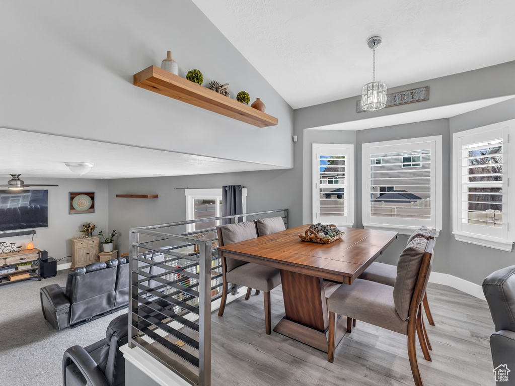Dining space featuring vaulted ceiling, plenty of natural light, light wood-style flooring, and a chandelier