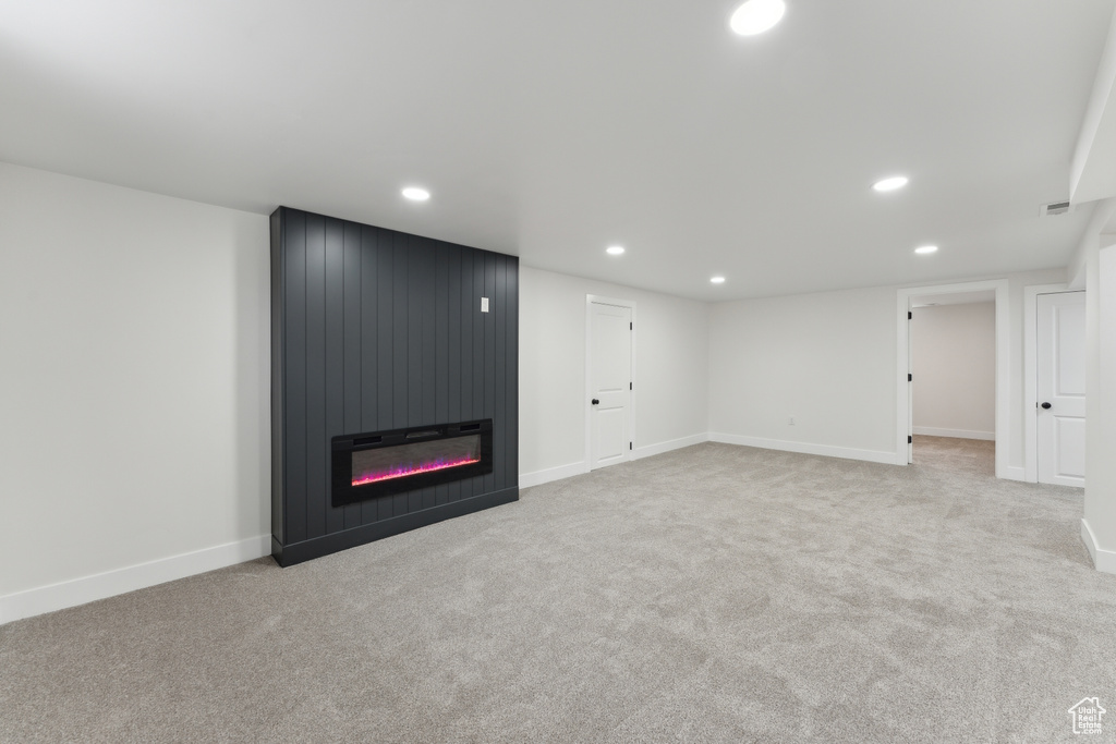 Unfurnished living room with recessed lighting, carpet floors, a large fireplace, and baseboards