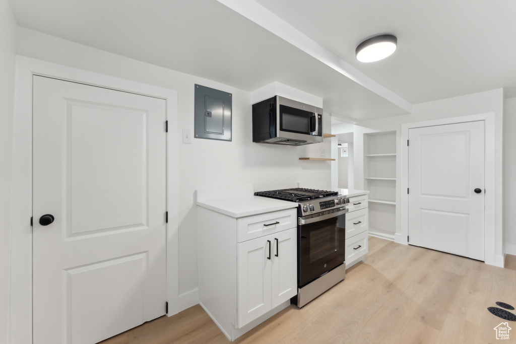 Kitchen featuring stainless steel appliances, electric panel, light wood-type flooring, light countertops, and white cabinetry