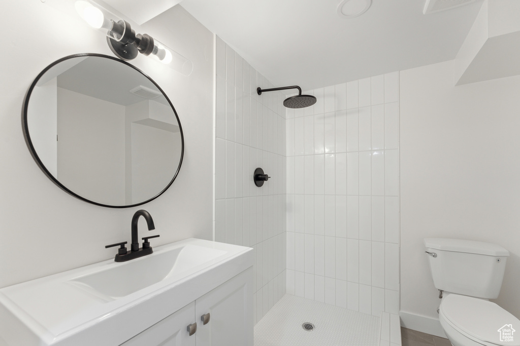 Bathroom with toilet, tiled shower, and vanity