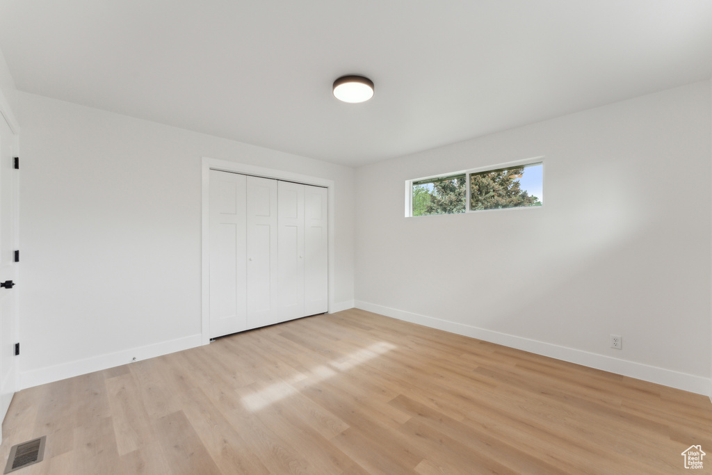 Unfurnished bedroom with baseboards, light wood-type flooring, and a closet