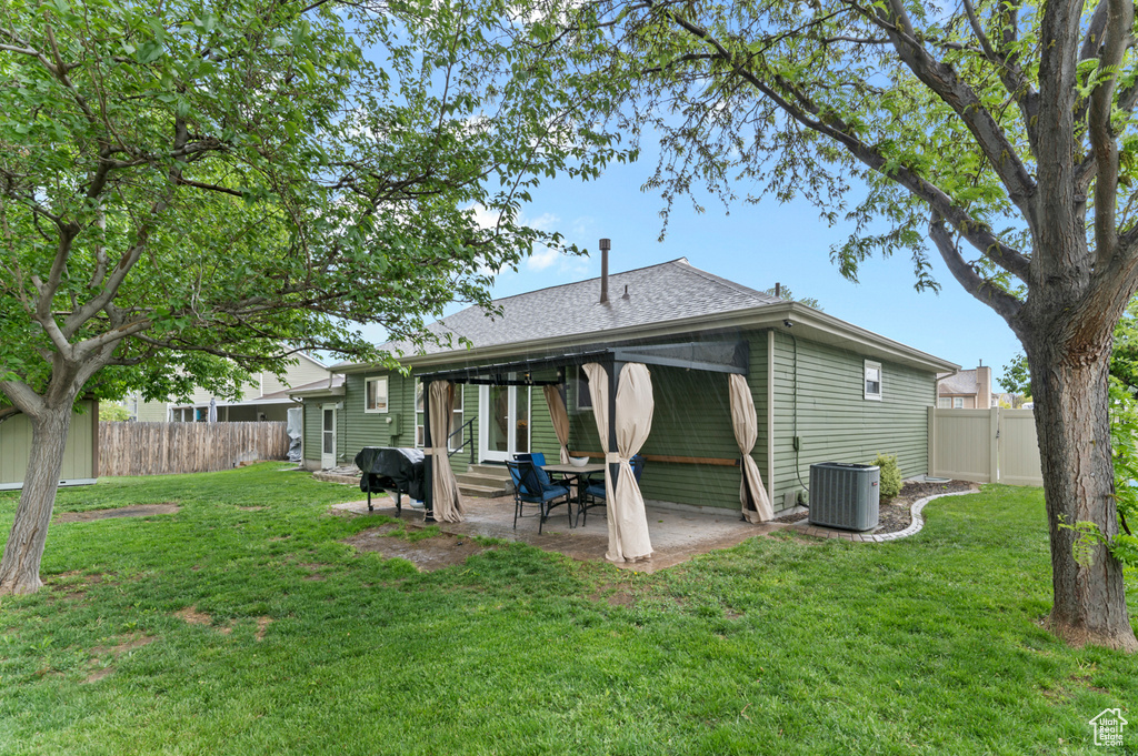 Back of property with a patio, cooling unit, a shingled roof, and a gate