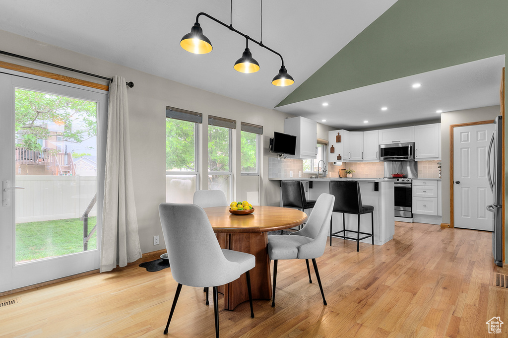 Dining area with light wood-type flooring, lofted ceiling, and recessed lighting