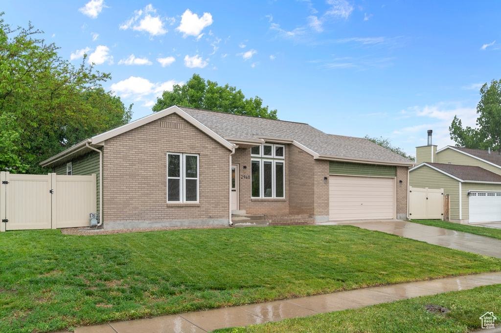 View of front facade with a gate, driveway, an attached garage, and brick siding
