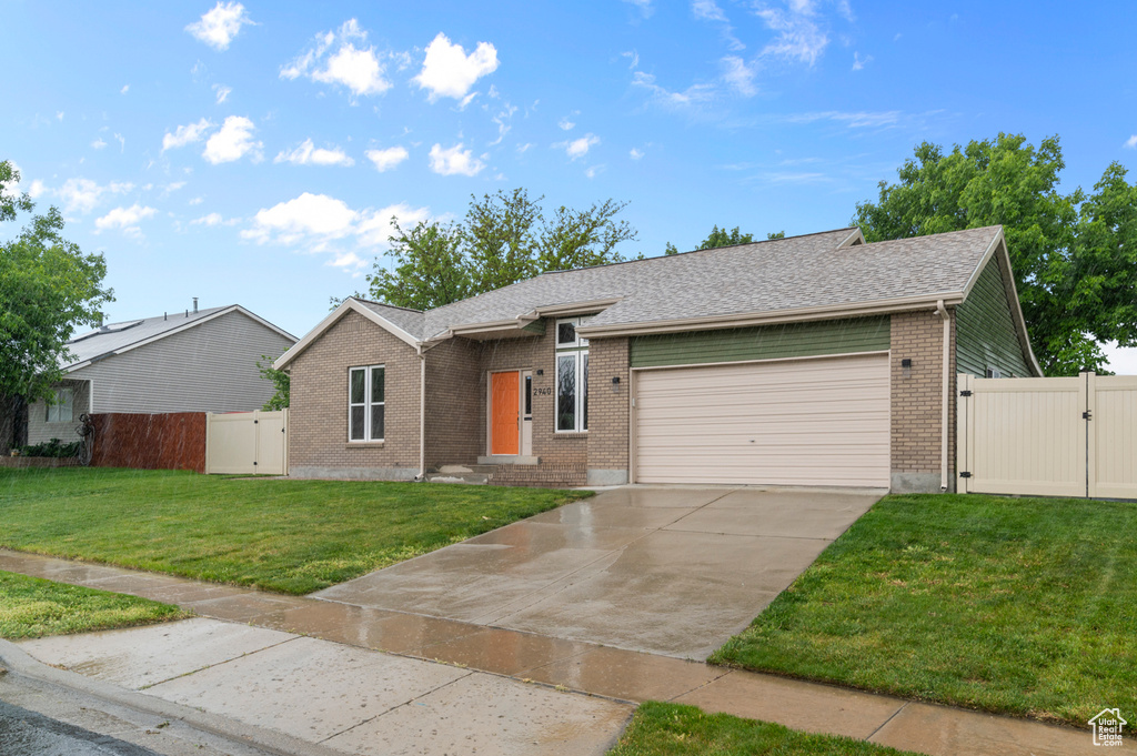 Ranch-style home featuring a gate, brick siding, an attached garage, and concrete driveway