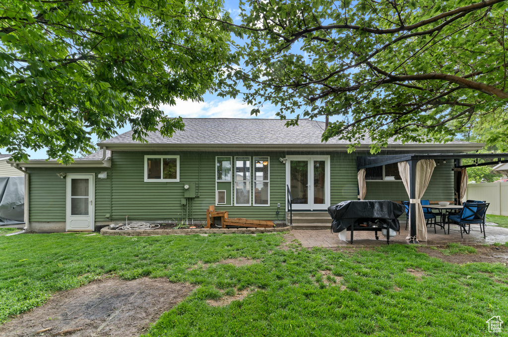 Rear view of house with entry steps, a patio, a yard, and french doors