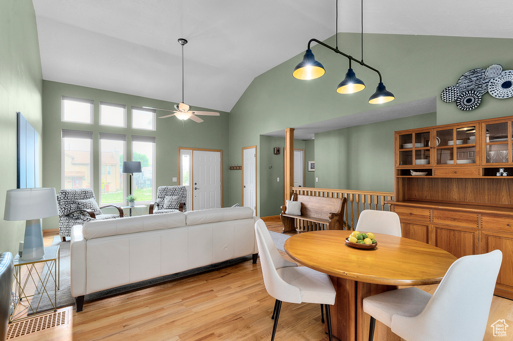 Dining area with ceiling fan, high vaulted ceiling, and light wood-style flooring