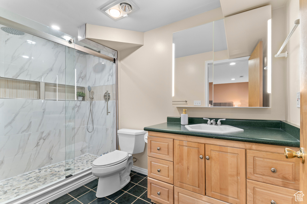 Full bathroom featuring toilet, a marble finish shower, tile patterned floors, vanity, and baseboards