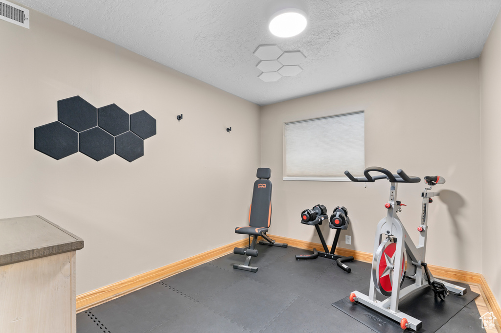 Exercise room with a textured ceiling and baseboards