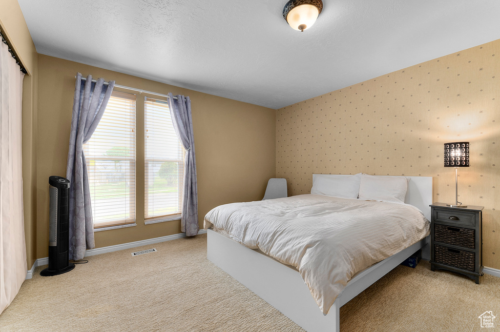 Bedroom with carpet flooring, baseboards, multiple windows, and wallpapered walls