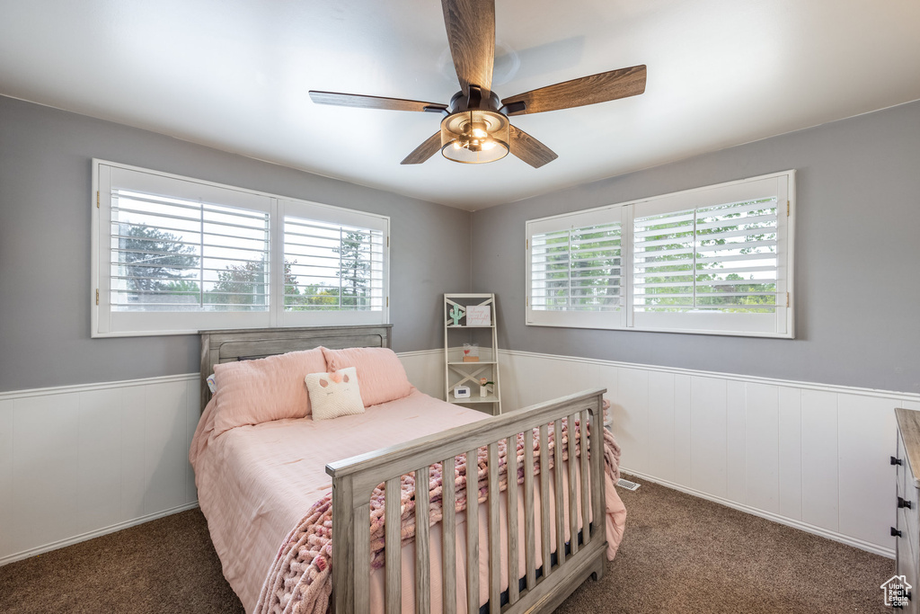 Carpeted bedroom with wainscoting and a ceiling fan