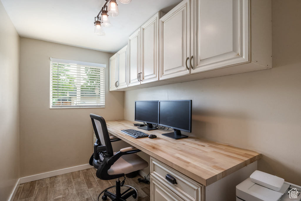 Home office featuring built in study area, wood finished floors, and baseboards