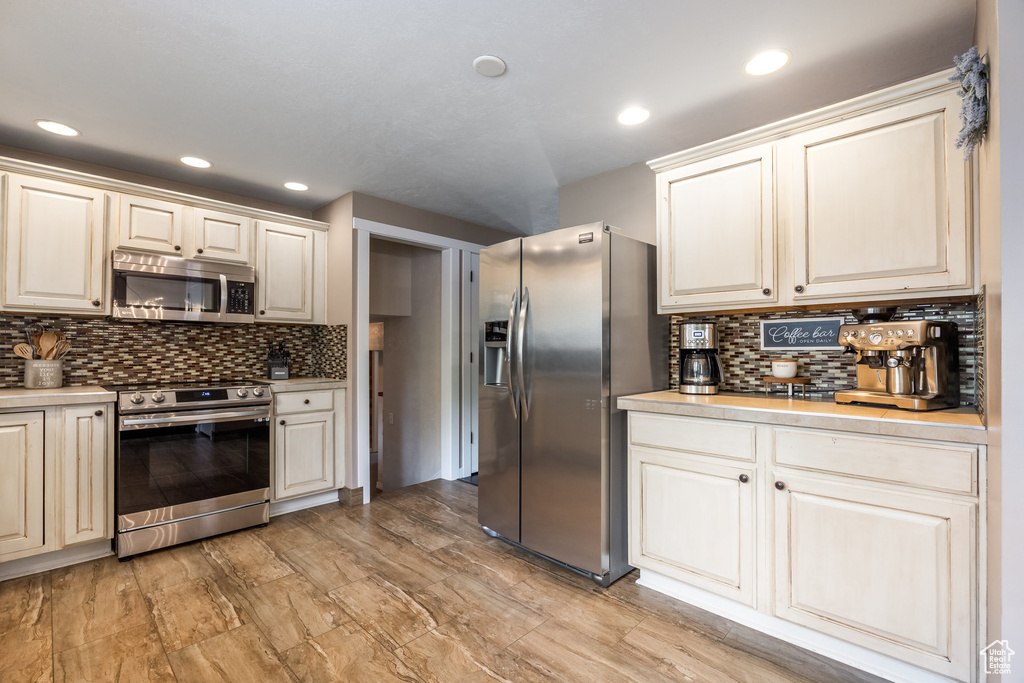 Kitchen featuring appliances with stainless steel finishes, decorative backsplash, light countertops, and recessed lighting