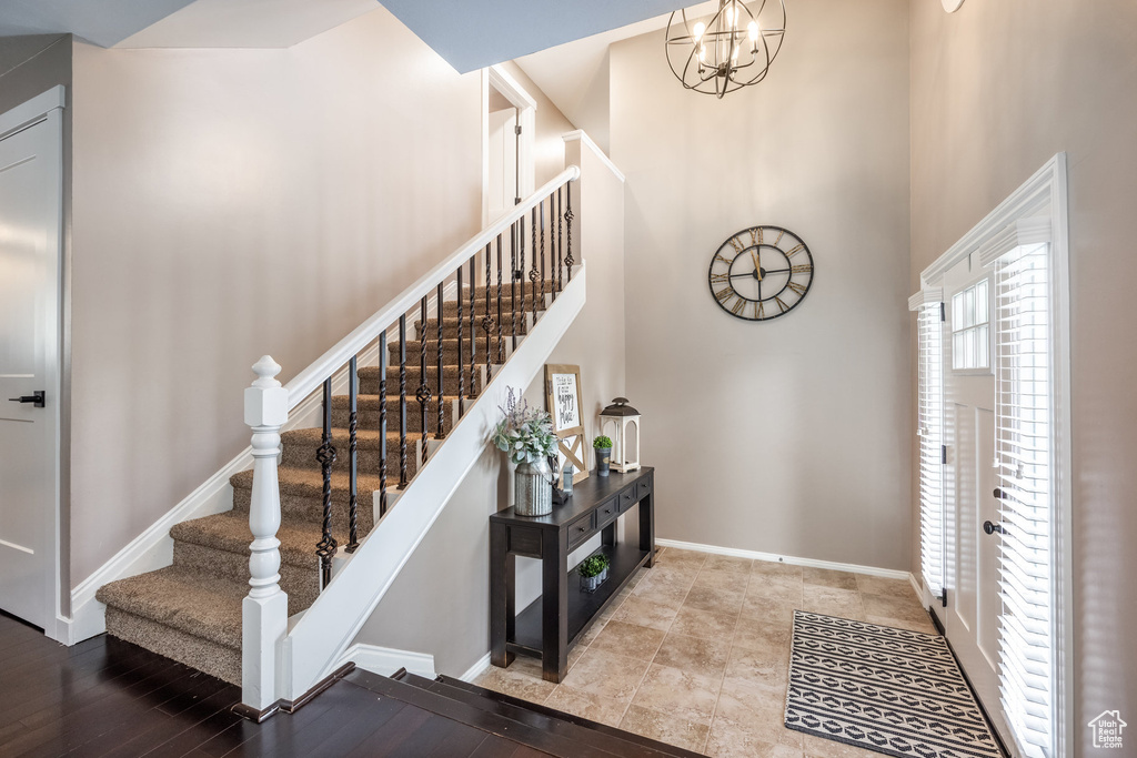 Foyer with a towering ceiling, stairs, baseboards, and a chandelier