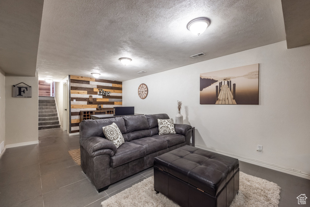 Living area with a textured ceiling, stairs, wooden walls, and baseboards