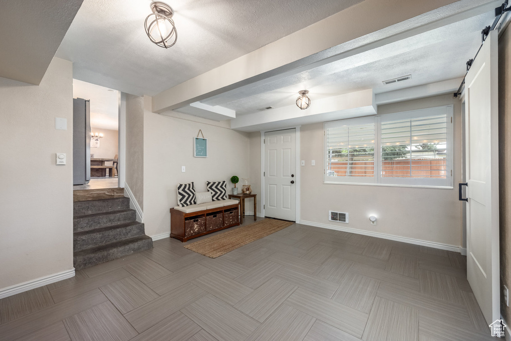 Foyer entrance featuring a barn door, stairs, and baseboards