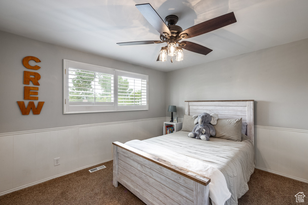 Bedroom featuring carpet floors, a wainscoted wall, and a ceiling fan