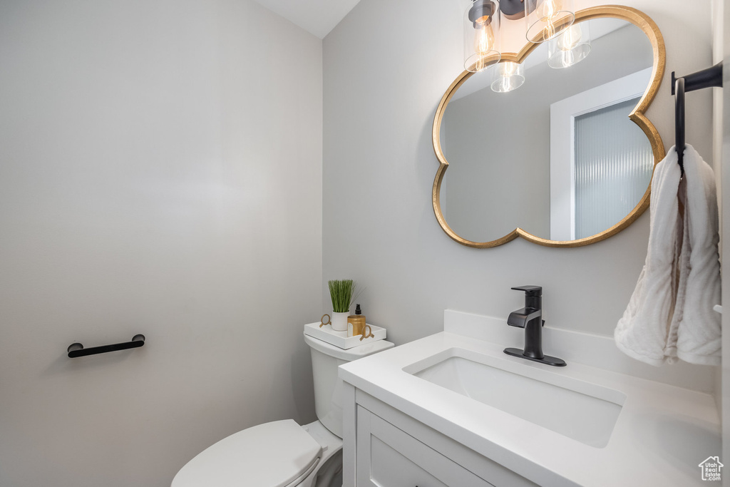 Half bathroom featuring a chandelier, vanity, and toilet