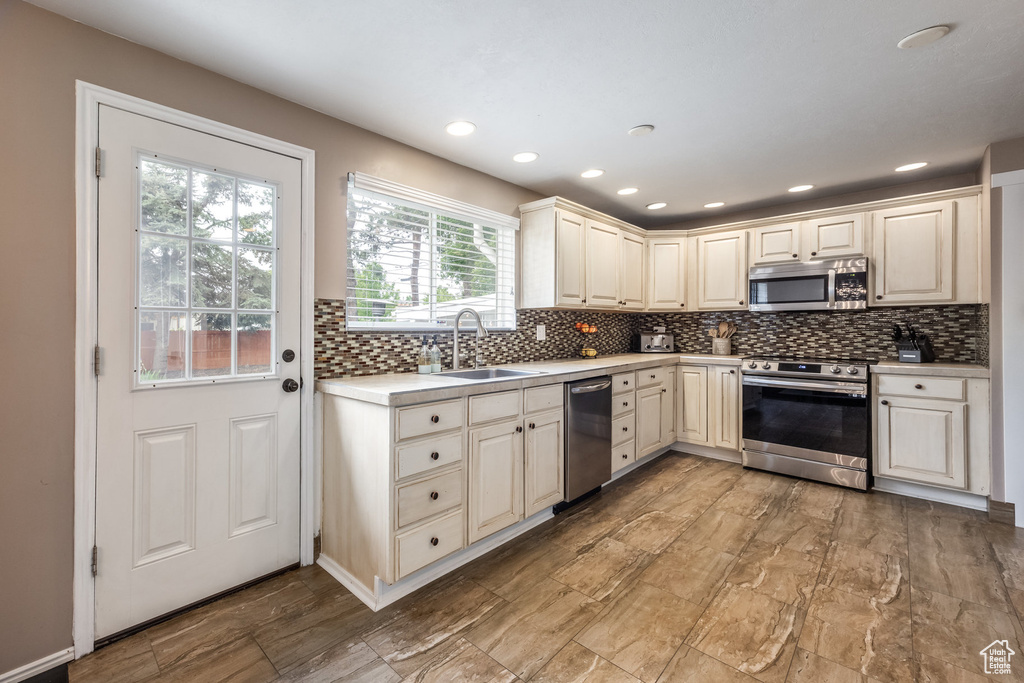 Kitchen featuring stainless steel appliances, a sink, light countertops, decorative backsplash, and recessed lighting