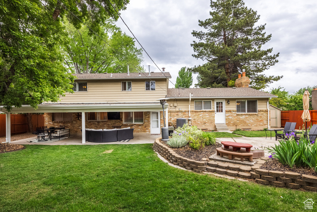 Back of property featuring a patio area, a chimney, an outdoor living space, and brick siding