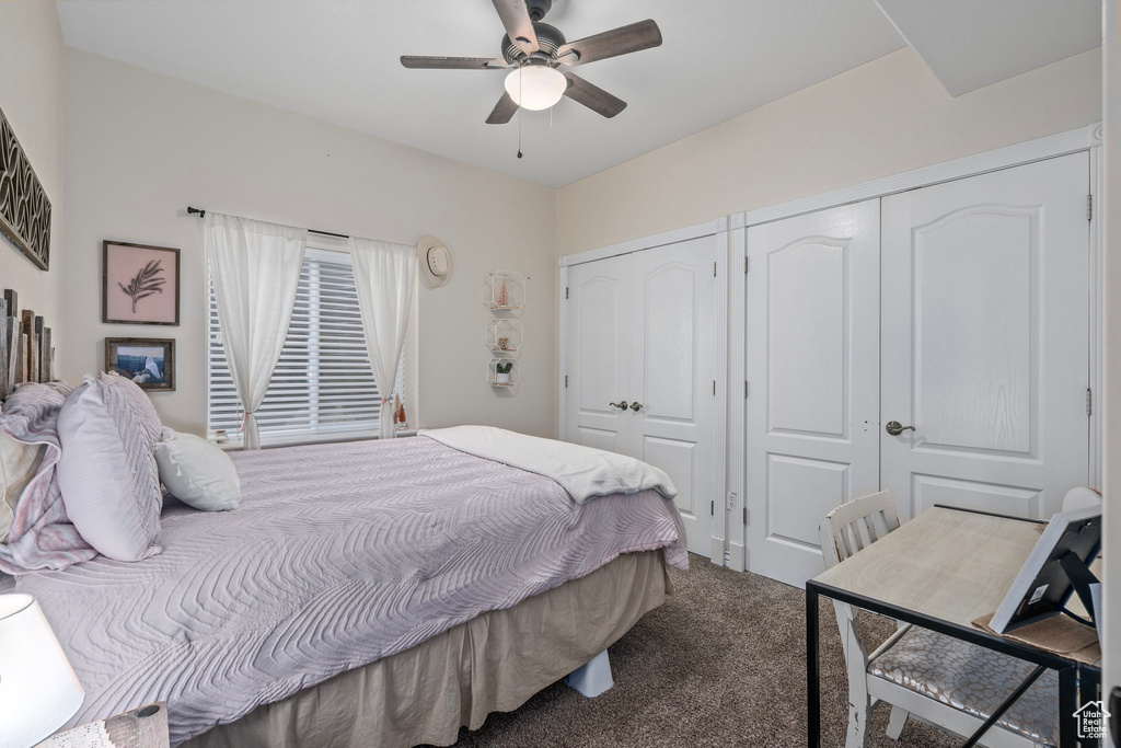 Carpeted bedroom with multiple closets and a ceiling fan